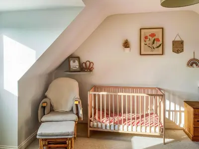 a baby room with a crib and a chair at Kerensa in St. Agnes