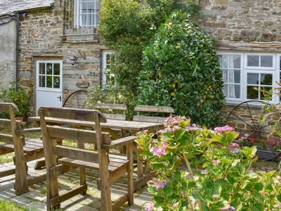 a wooden table and chairs in front of a building at Stables - Uk50372 in Camelford