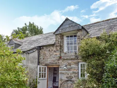 an old stone house with a white door at Stables - Uk50372 in Camelford