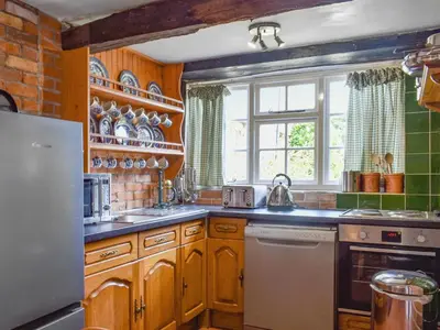 a kitchen with wooden cabinets and a window at Stables - Uk50372 in Camelford
