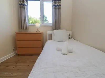 a bedroom with a white bed with a dresser and a window at 28 Guildford Road in Hayle