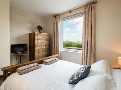 a bedroom with a large white bed with a window at VARLEY VIEW Fishermans cottage with stunning views in Port Isaac