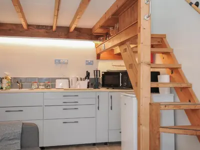 a kitchen with white cabinets and a wooden ladder at Little Coombe in Liskeard