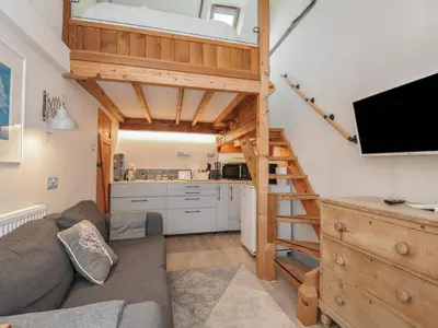 a living room with a loft bed and a kitchen at Little Coombe in Liskeard
