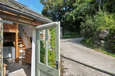 a door leading into a cottage with a pathway at Little Coombe in Liskeard