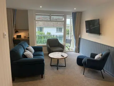 a living room with a couch and two chairs and a table at Beachy Maisonette- 2 Min walk to Porth Beach in Newquay