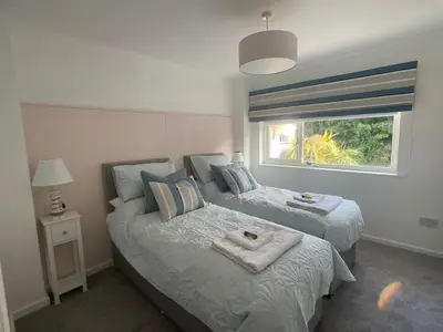 a bedroom with two beds and a window at Beachy Maisonette- 2 Min walk to Porth Beach in Newquay