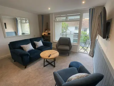 a living room with a blue couch and a table at Beachy Maisonette- 2 Min walk to Porth Beach in Newquay