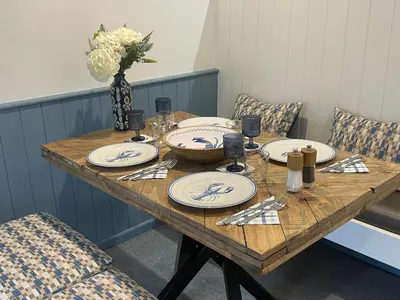 a wooden table with plates and a vase of flowers at Beachy Maisonette- 2 Min walk to Porth Beach in Newquay