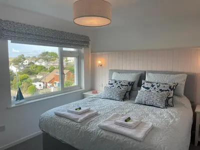 a bedroom with a bed with towels and a window at Beachy Maisonette- 2 Min walk to Porth Beach in Newquay