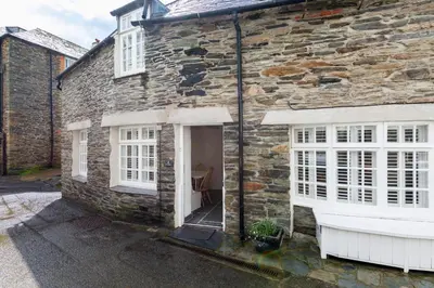 an old stone house with white windows and a door at Cor anglais in Port Isaac