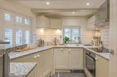 a kitchen with white cabinets and granite counter tops at Cor anglais in Port Isaac