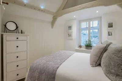 a bedroom with a bed and a dresser and a window at Cor anglais in Port Isaac