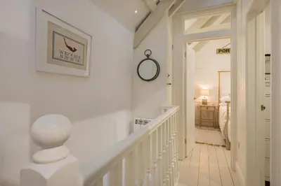 a hallway with a white staircase with a picture on the wall at Cor anglais in Port Isaac
