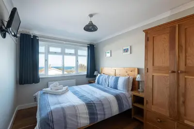 a bedroom with a bed and a window at Silvershell House in Port Isaac