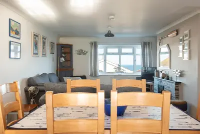 a dining room and living room with a table and chairs at Silvershell House in Port Isaac