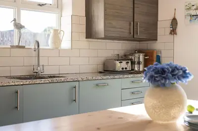 a kitchen with blue cabinets and a sink and a counter at Silvershell House in Port Isaac