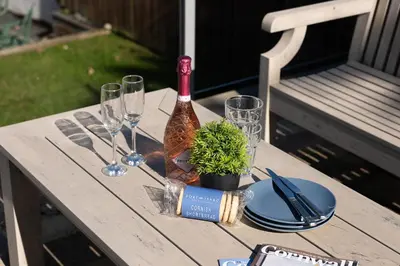 a table with a bottle of wine and glasses on it at Silvershell House in Port Isaac