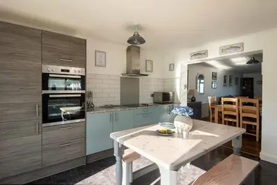 a kitchen with blue cabinets and a table in it at Silvershell House in Port Isaac