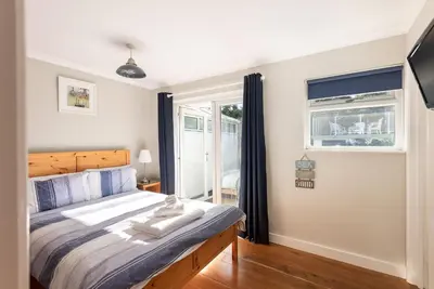 a bedroom with a large bed and a window at Silvershell House in Port Isaac