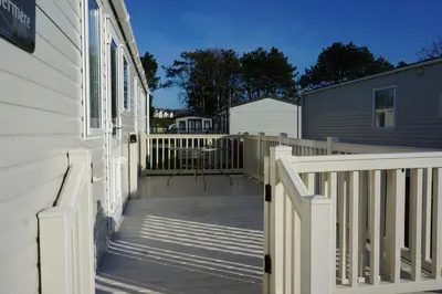a deck with a white fence next to a house at Sarahs Retreat in Par