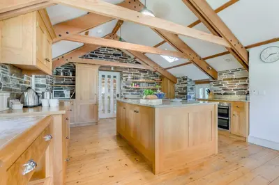 a large kitchen with wooden cabinets and wooden floors at 6 Bed in Tresillian oc-t32987 in Newlyn East