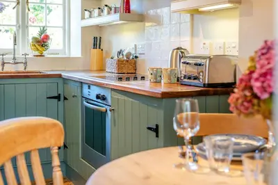 a kitchen with green cabinets and a table with wine glasses at 1 Bed in Tresillian oc-t32988 in Newlyn East