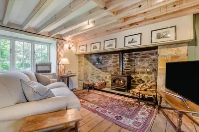 a living room with a stone fireplace and a tv at 1 Bed in Tresillian oc-t32988 in Newlyn East