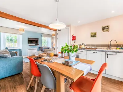 a kitchen and living room with a wooden table and chairs at Holiday Home Cherry Orchards by Interhome in Mevagissey