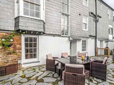 a patio with a table and chairs in front of a building at Holiday Home Cherry Orchards by Interhome in Mevagissey