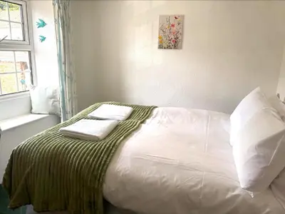 a bed with a green and white blanket on it at Holiday Home Rosehip Cottage by Interhome in Pentewan
