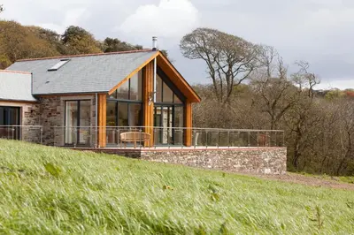 a house on a grassy hill with a building at Callestock Vean in Truro