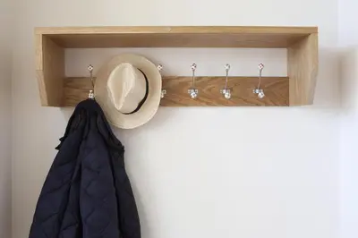 a hat on a wooden shelf with a curtain and hooks at Callestock Vean in Truro
