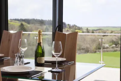 a bottle of wine sitting on a table with glasses at Callestock Vean in Truro