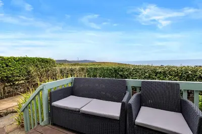 a wicker chair sitting on a balcony overlooking the ocean at Finest Retreats - Sea Thrift at Widemouth Bay in Widemouth Bay