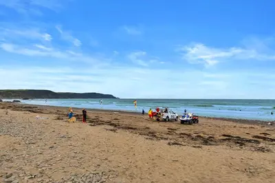 a group of people standing on a sandy beach at Finest Retreats - Sea Thrift at Widemouth Bay in Widemouth Bay