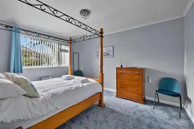 a bedroom with a canopy bed and a blue chair at Finest Retreats - Sea Thrift at Widemouth Bay in Widemouth Bay