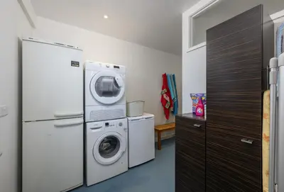 a laundry room with a refrigerator and a washer and dryer at The Gatehouse Apartment in Portreath