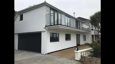 a white house with a lot of windows at Gannel View Apartment in Newquay
