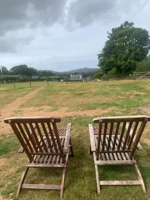 two wooden chairs sitting in the grass in a field at Rosies in Liskeard