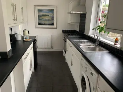 a kitchen with white cabinets and a sink at 2 Bed-Sleeps 4-Parking-Pets-10 min walk to Beach in Falmouth