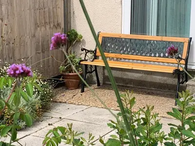 a wooden bench sitting next to some potted plants at 2 Bed-Sleeps 4-Parking-Pets-10 min walk to Beach in Falmouth