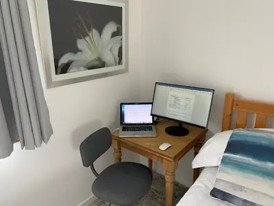 a desk with a laptop and a computer on it next to a bed at 2 Bed-Sleeps 4-Parking-Pets-10 min walk to Beach in Falmouth