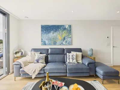 a living room with a blue couch and a table at Skydeck at The Liner – Stylish 2-Bed / 2-Bath Top Floor with Panoramic Sea Views in Falmouth