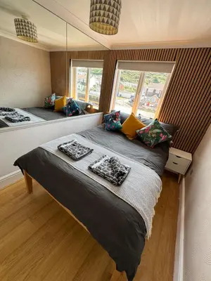 a bedroom with two beds and a large window at Harbour Edge in Portreath