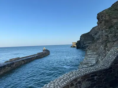 a person standing on a rock wall next to the ocean at Harbour Edge in Portreath
