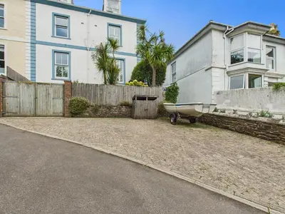 a house with a boat parked in front of a driveway at Cosy Coastal Falmouth Studio with Free parking & WiFi in Falmouth