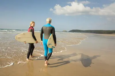 two men walking on the beach with their surfboards at Cosy Coastal Falmouth Studio with Free parking & WiFi in Falmouth
