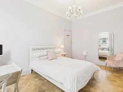 a white bedroom with a white bed and a chair at Cosy Coastal Falmouth Studio with Free parking & WiFi in Falmouth