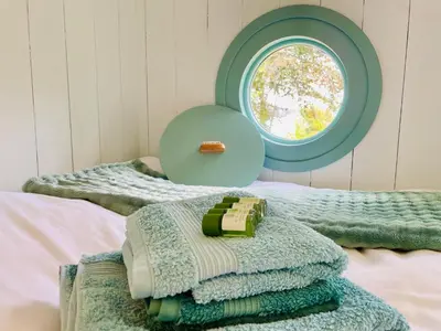a pile of towels on a bed with a window at Sea Spray in St Austell